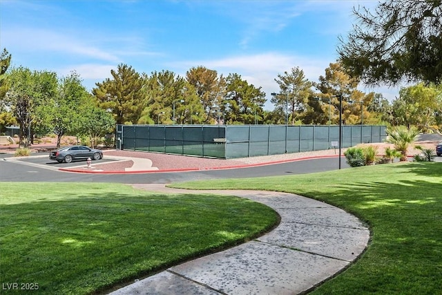 view of tennis court featuring a yard and fence