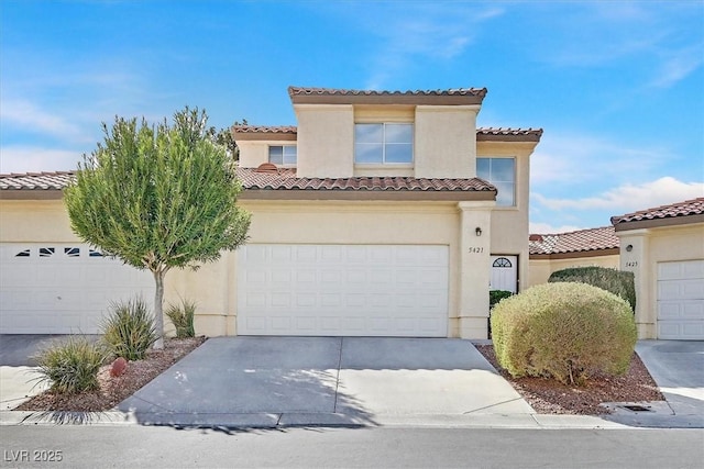 mediterranean / spanish-style house with driveway, a tiled roof, and stucco siding