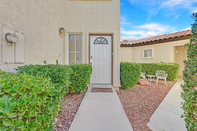 property entrance with a tile roof and stucco siding