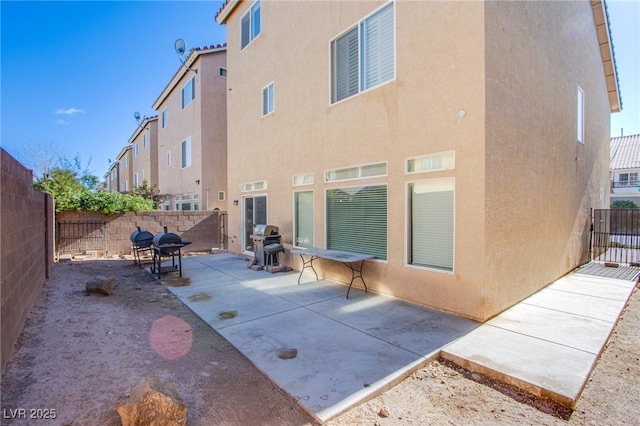 rear view of property featuring a patio area, a fenced backyard, and stucco siding