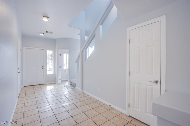 foyer entrance with light tile patterned floors, baseboards, and visible vents