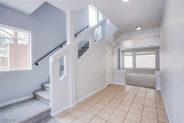 stairs with carpet floors, tile patterned flooring, and baseboards