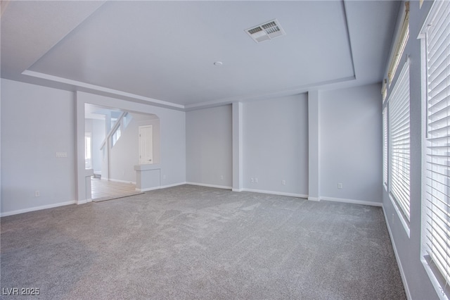 empty room featuring baseboards, a tray ceiling, visible vents, and carpet flooring