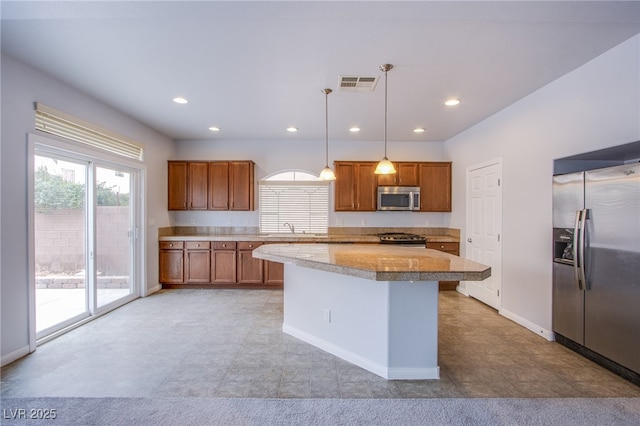 kitchen featuring tile countertops, visible vents, appliances with stainless steel finishes, brown cabinetry, and pendant lighting