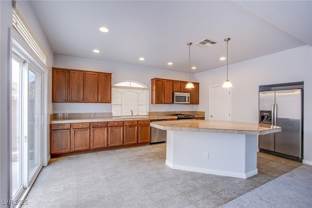 kitchen with stainless steel appliances, a center island, hanging light fixtures, light countertops, and brown cabinets