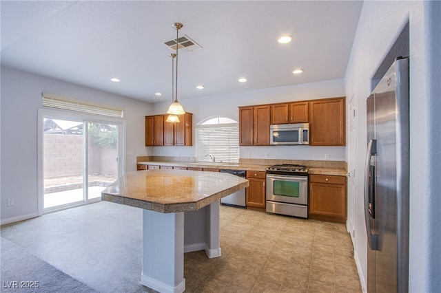 kitchen featuring stainless steel appliances, brown cabinets, visible vents, and hanging light fixtures