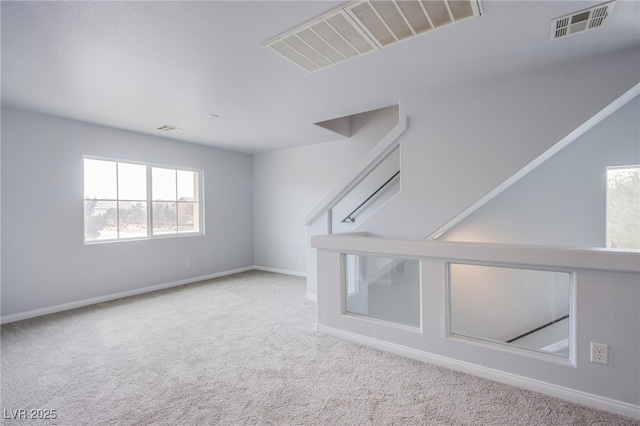 carpeted spare room featuring baseboards and visible vents