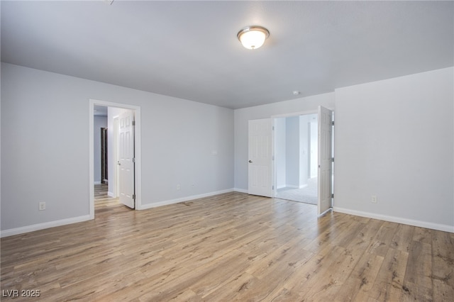 empty room with baseboards and light wood-style floors