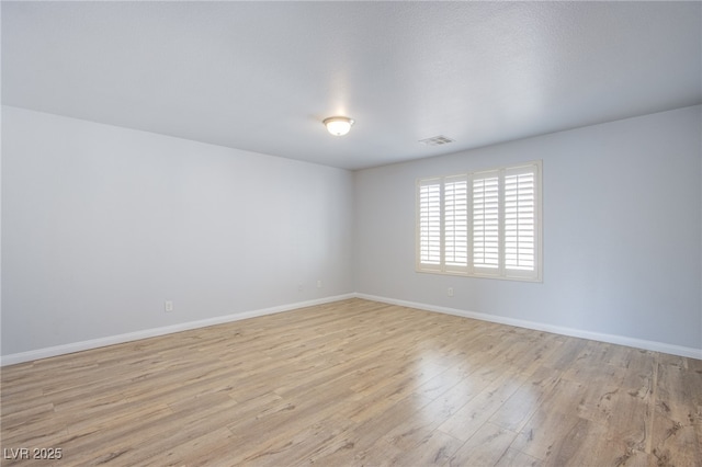 unfurnished room featuring visible vents, light wood-style flooring, and baseboards