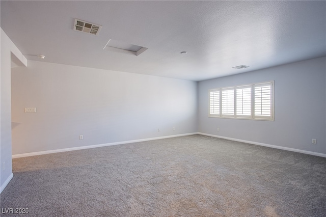 spare room featuring carpet floors, attic access, visible vents, and baseboards