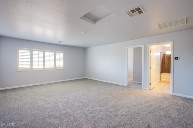 spare room featuring attic access, visible vents, light carpet, and baseboards