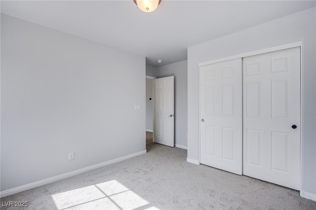 unfurnished bedroom with baseboards, a closet, and light colored carpet