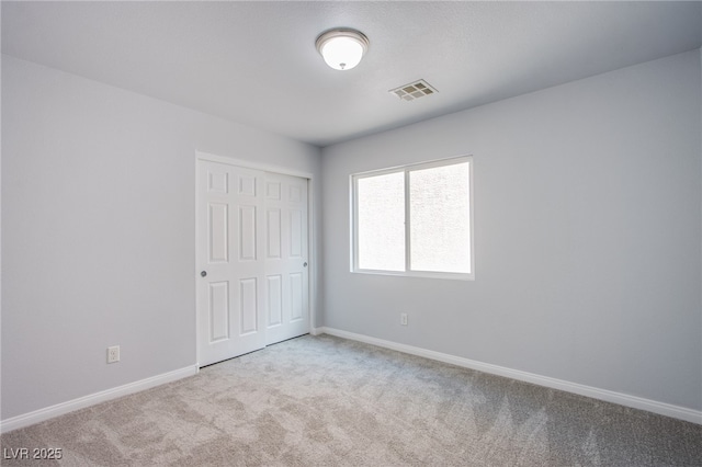 unfurnished bedroom with light carpet, a closet, visible vents, and baseboards