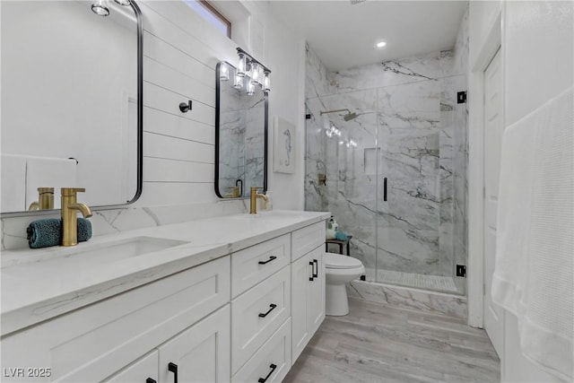 bathroom featuring toilet, double vanity, a sink, and a marble finish shower