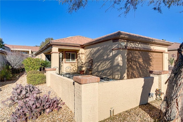 view of front of home featuring a garage, driveway, a fenced front yard, and stucco siding