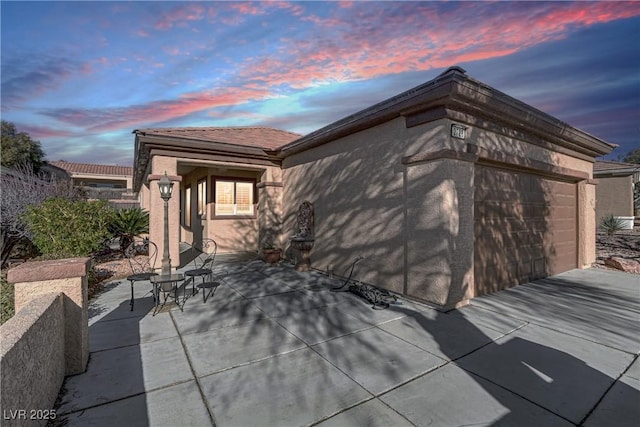 exterior space with a patio, an attached garage, and stucco siding