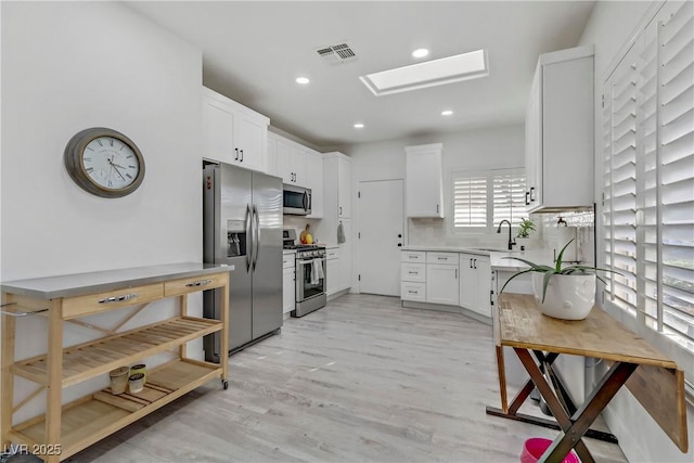 kitchen with a sink, visible vents, white cabinets, light countertops, and appliances with stainless steel finishes