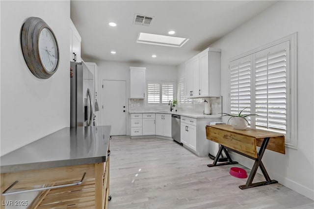 kitchen featuring stainless steel appliances, light countertops, visible vents, and white cabinetry