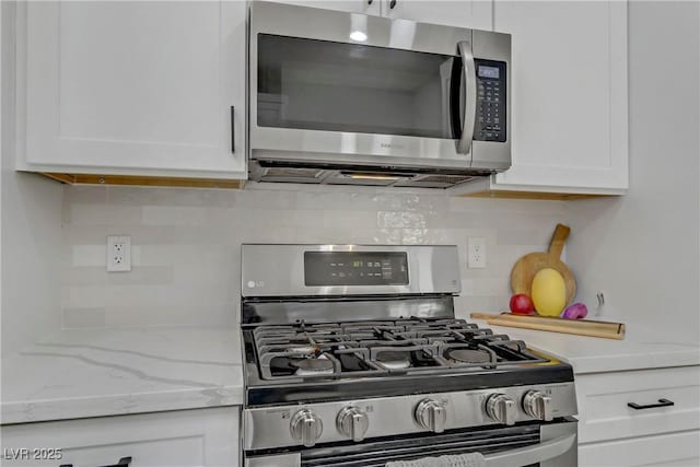 kitchen featuring stainless steel appliances, tasteful backsplash, light stone countertops, and white cabinets