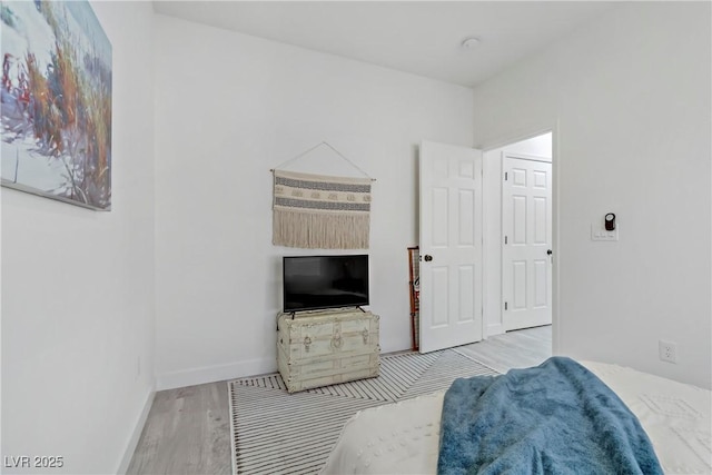 bedroom featuring light wood finished floors and baseboards