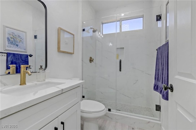 bathroom with toilet, a marble finish shower, and vanity