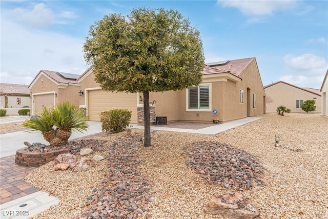 view of front of house featuring solar panels, a tile roof, concrete driveway, stucco siding, and a garage