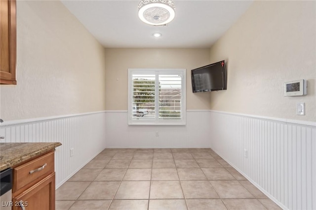 spare room with light tile patterned floors and a wainscoted wall