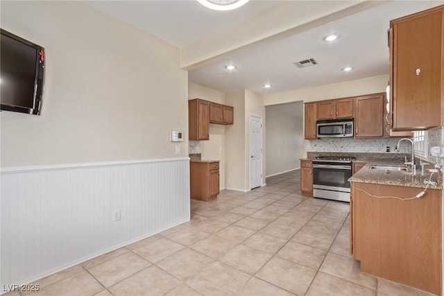 kitchen with visible vents, brown cabinets, a sink, tasteful backsplash, and appliances with stainless steel finishes