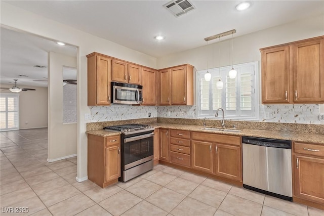 kitchen featuring visible vents, a sink, decorative backsplash, appliances with stainless steel finishes, and brown cabinets