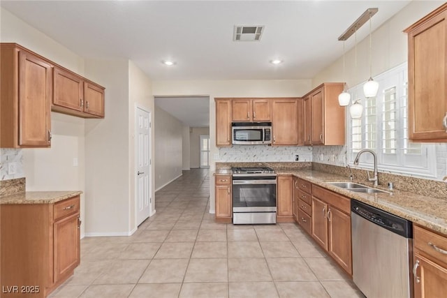 kitchen with tasteful backsplash, visible vents, light stone countertops, appliances with stainless steel finishes, and a sink