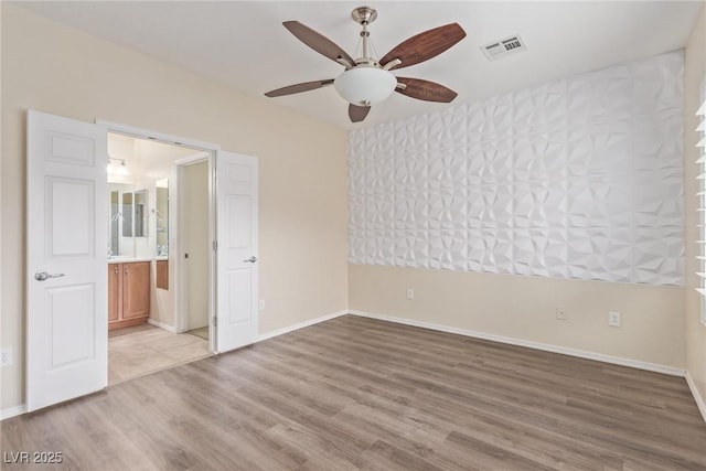 unfurnished bedroom featuring visible vents, light wood-style flooring, connected bathroom, and baseboards