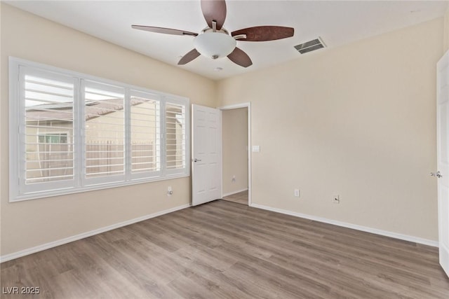 spare room with visible vents, baseboards, and wood finished floors