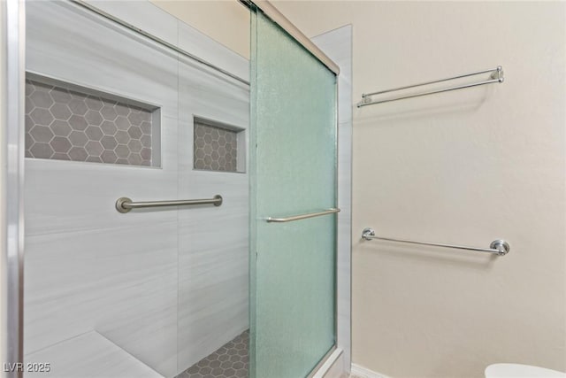 bathroom featuring toilet and a shower with shower door