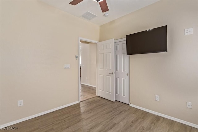 unfurnished bedroom featuring visible vents, a ceiling fan, wood finished floors, a closet, and baseboards