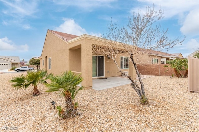 rear view of property with a patio area, stucco siding, and fence