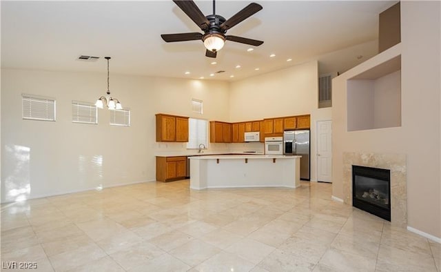 kitchen with white appliances, a kitchen island, light countertops, brown cabinets, and a kitchen bar