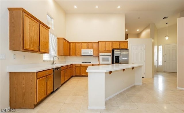 kitchen with stainless steel appliances, a towering ceiling, light countertops, a center island, and pendant lighting