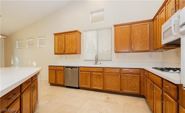 kitchen featuring brown cabinets, white appliances, light countertops, and a sink