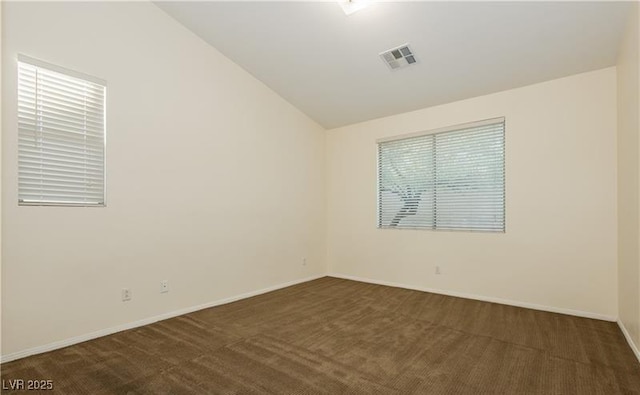 unfurnished room with lofted ceiling, dark carpet, visible vents, and baseboards