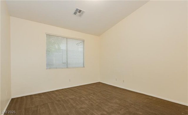 empty room with lofted ceiling, baseboards, visible vents, and dark colored carpet