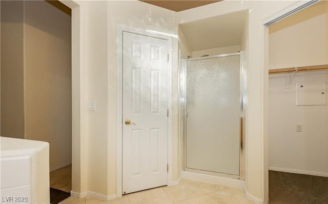 bathroom with a stall shower, baseboards, and tile patterned floors