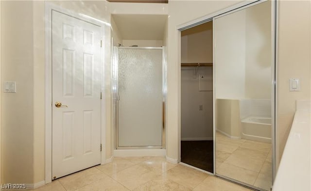 bathroom with tile patterned flooring, baseboards, a closet, a bath, and a stall shower