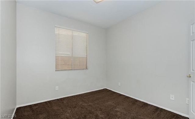 empty room featuring baseboards and dark colored carpet