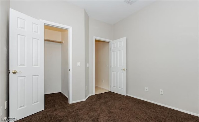 unfurnished bedroom featuring baseboards, dark colored carpet, and a closet