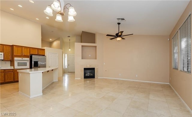 kitchen featuring white appliances, brown cabinetry, open floor plan, decorative light fixtures, and light countertops