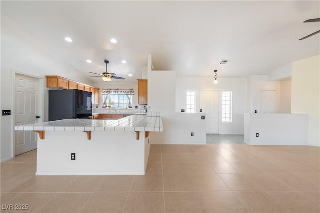 kitchen featuring tile countertops, a peninsula, fridge, and a kitchen breakfast bar