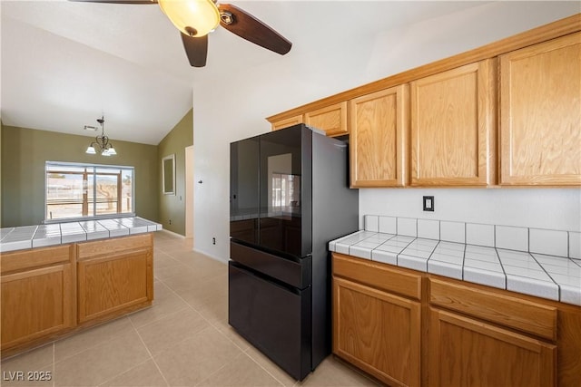 kitchen with tile countertops, light tile patterned floors, lofted ceiling, and freestanding refrigerator