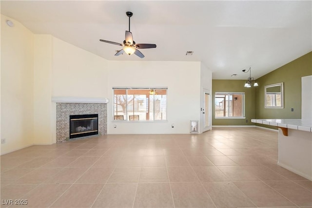 unfurnished living room with a fireplace, lofted ceiling, visible vents, light tile patterned flooring, and ceiling fan with notable chandelier