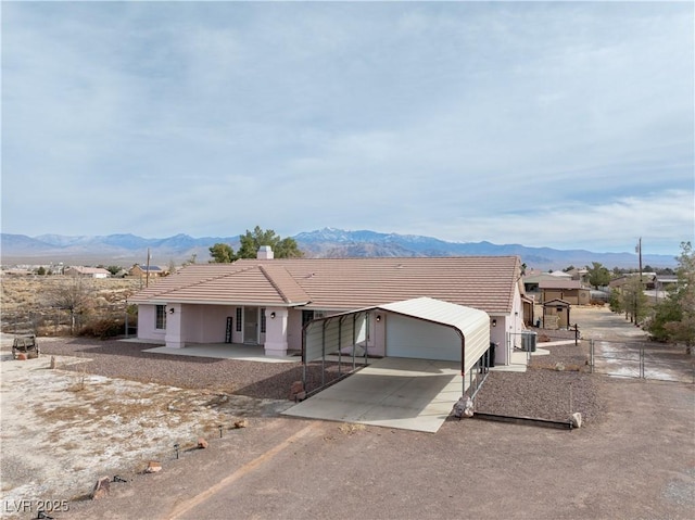 ranch-style house featuring a mountain view, an outdoor structure, a tile roof, fence, and dirt driveway