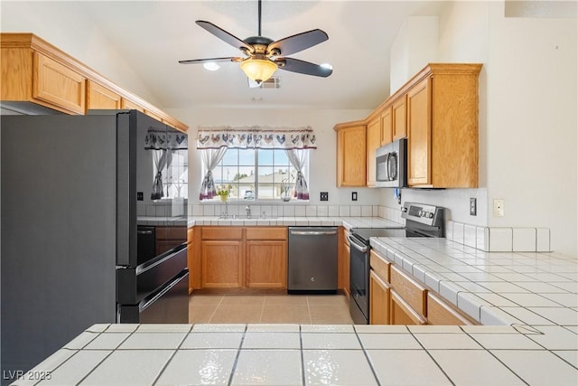 kitchen featuring stainless steel appliances, light tile patterned flooring, and tile counters